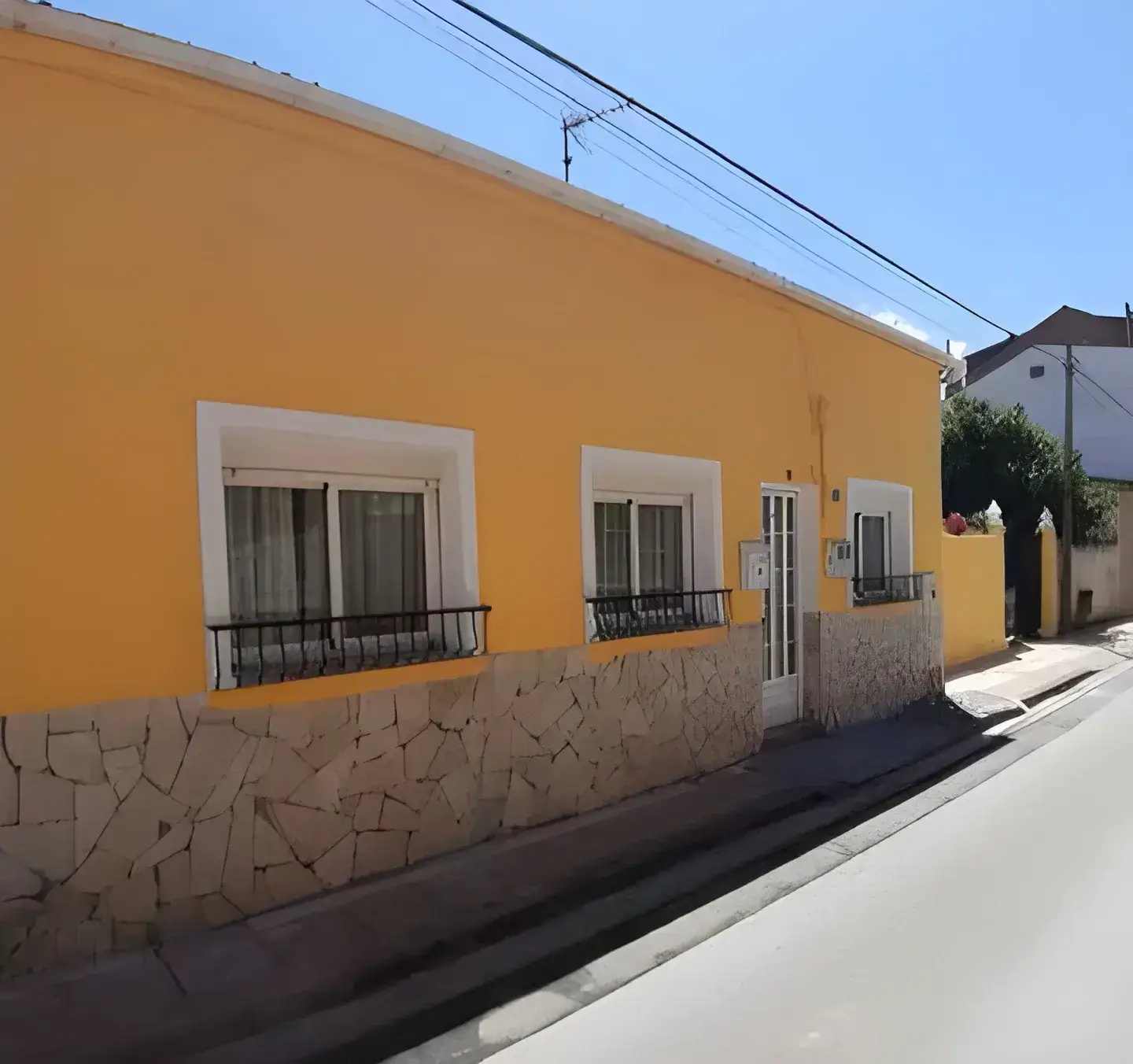 Pintor en Cartagena Fachada de casa tradicional pintada en color amarillo con zócalo de piedra