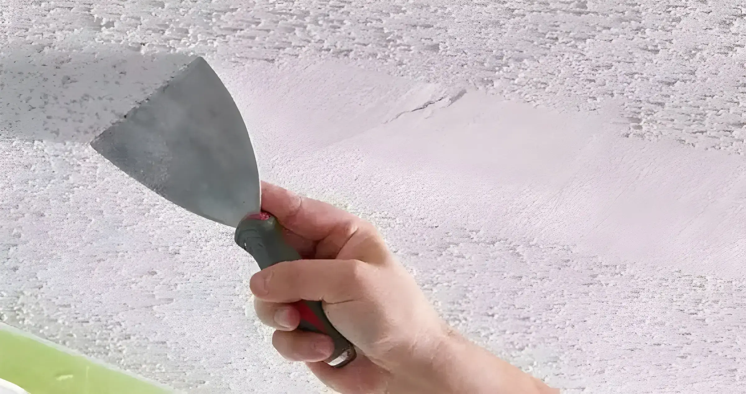 Pintor en Cartagena eliminando el gotelé con espátula para dejar la pared lisa